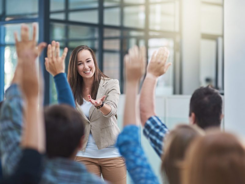 Shot of a group of people raising their hands in a seminar
